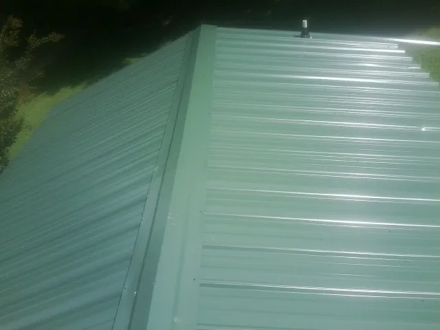 New green metal panels meeting at the ridge of a roof — Flat Roof Repair work by our crew in Santa Clara