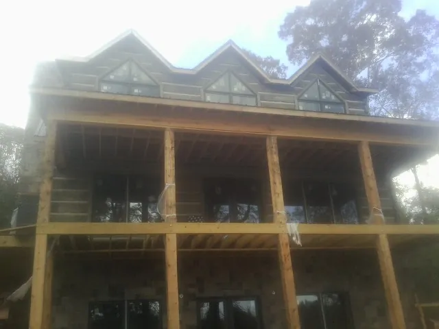 Dormers and porch framing on a large log home under construction — Roof Coating work by our crew in Santa Clara